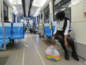 A photo of a girl in the Montréal metro, alone and looking behind her, holding a deflated balloon.